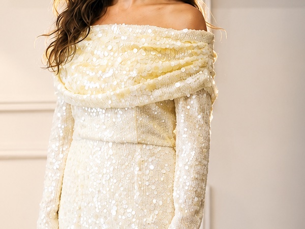 Ivory sequinned gown with a draped off-shoulder neckline and long sleeves